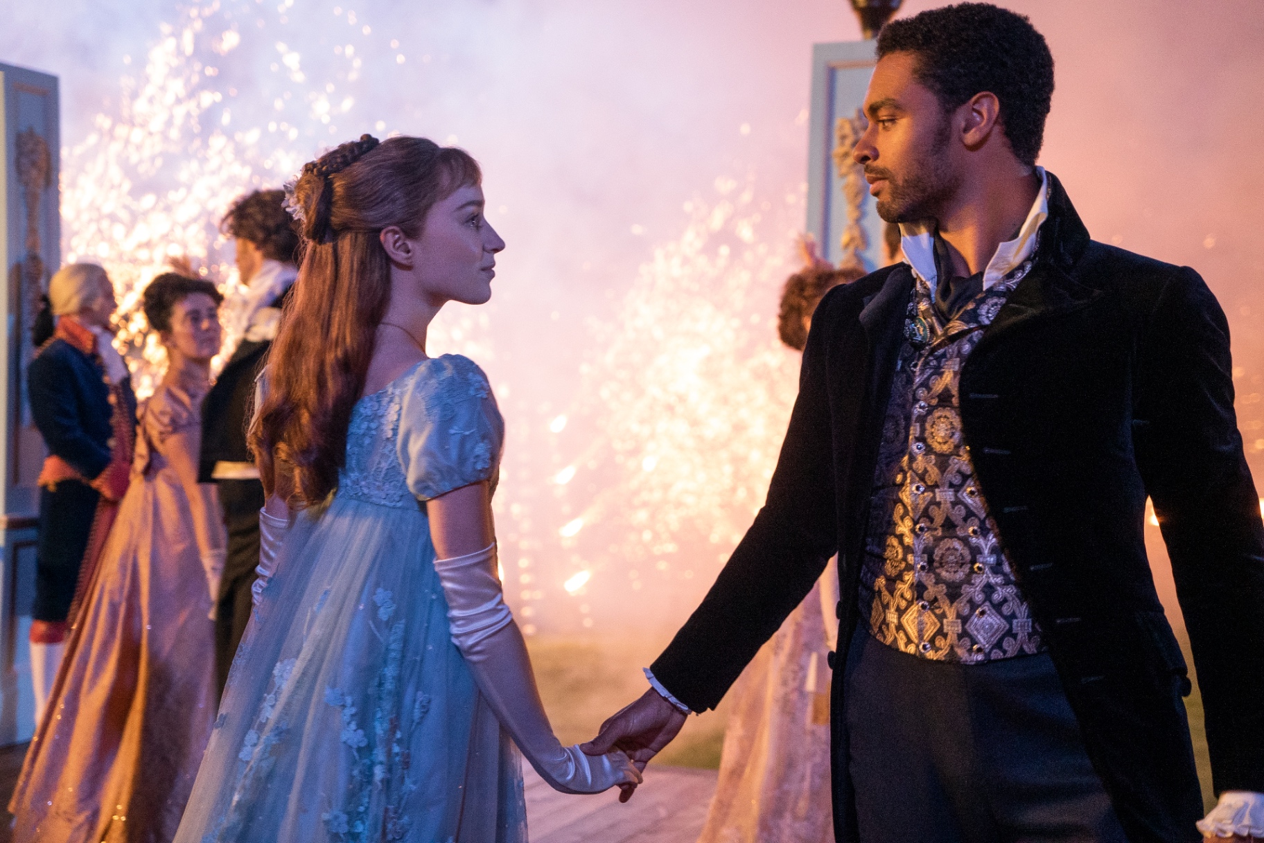 Daphne and the Duke hold hands in front of fireworks at the Bridgerton Queen's Ball